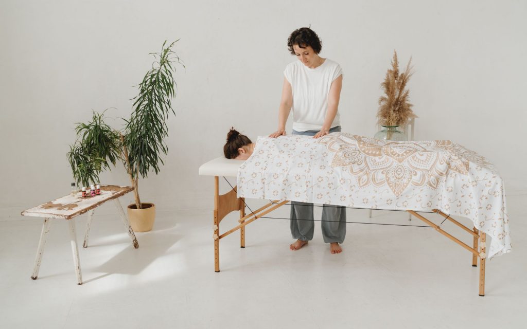 Doreen alias Ellie Lieb legt ihre Hände sanft auf den Rücken einer entspannten Klientin bei einer mobilen Massage zu Hause in Leipzig